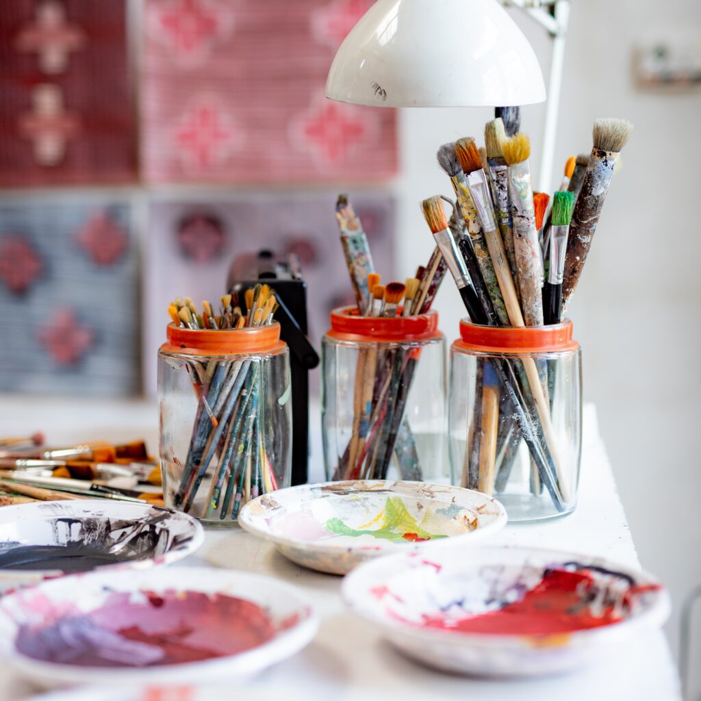 Backdrop of paintbrushes in jars, and dishes of